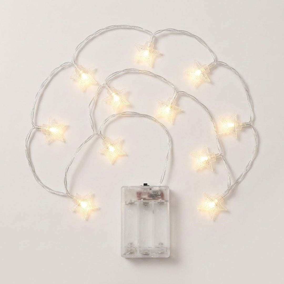 Warm white star-shaped fairy string lights with a clear battery compartment, arranged on a plain light background.