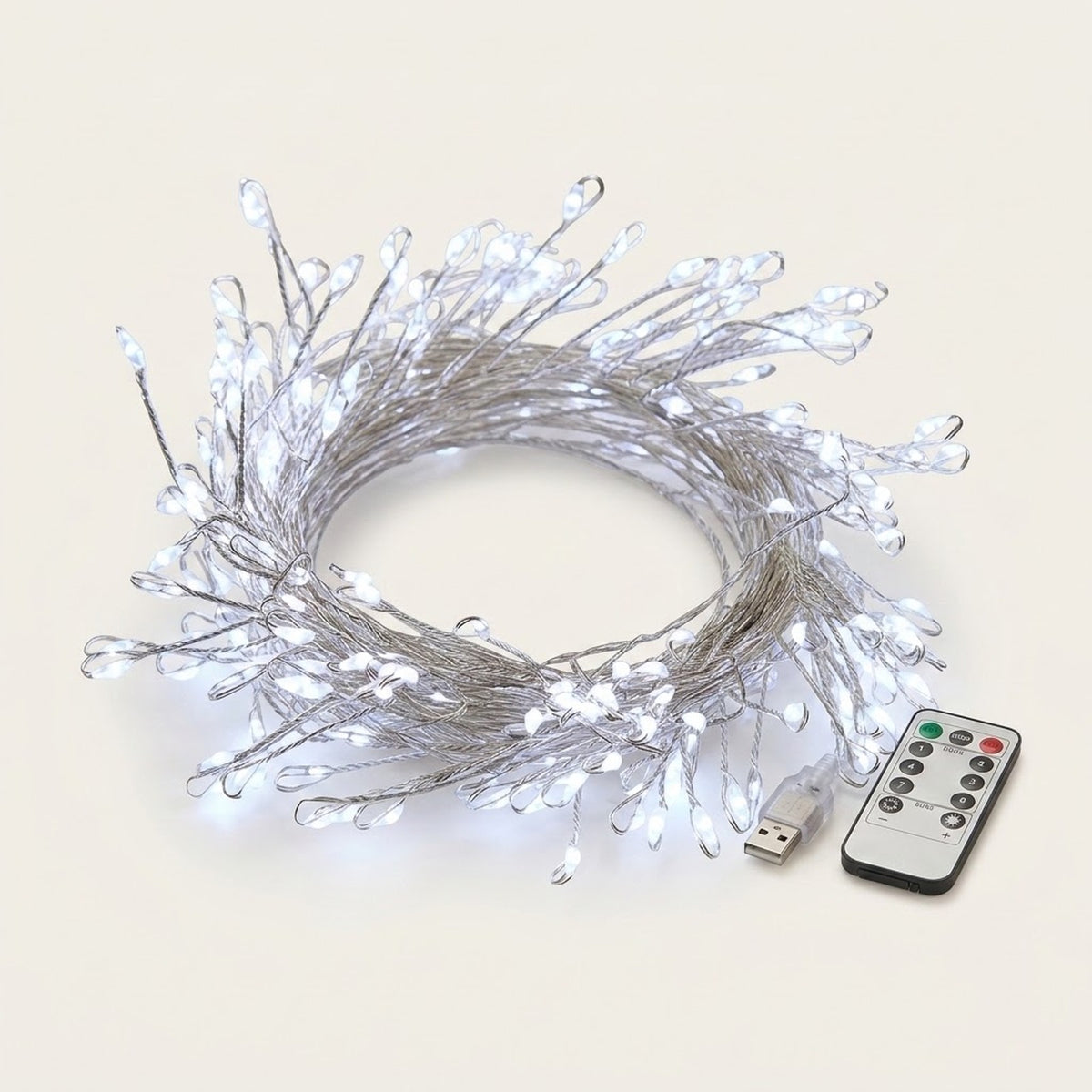 White LED fairy string lights with clear teardrop-shaped bulbs on a silver wire, shown coiled with a USB charging cable and a small remote control on a light beige background.