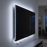 A wall-mounted flat-screen TV with a vertical strip of bright LED light along the left edge, casting a soft glow on the wall. A white power cable hangs below the TV, and the scene is shown in a modern living room setting.
