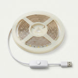 A coiled LED strip light with a white USB cable, inline switch, and USB connector, shown on a clean off-white background.