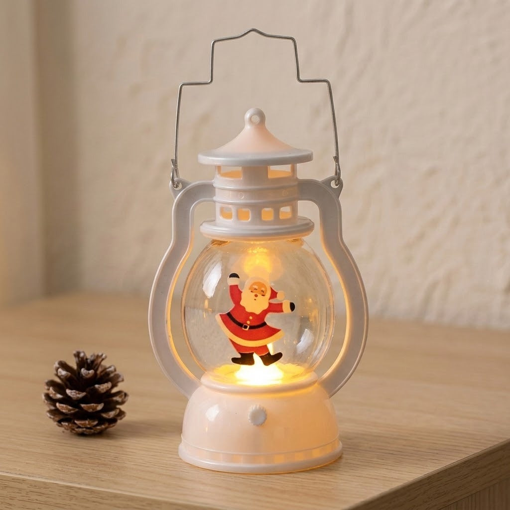 A white decorative lantern with a clear shade and glowing dancing Santa stands on a wooden tabletop beside a pinecone.