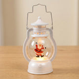 A white decorative lantern with dancing Santa and warm illumination stands alone on a light wooden tabletop against a cream background.