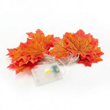 Artificial autumn maple leaf string lights with a small clear battery box on a white background.