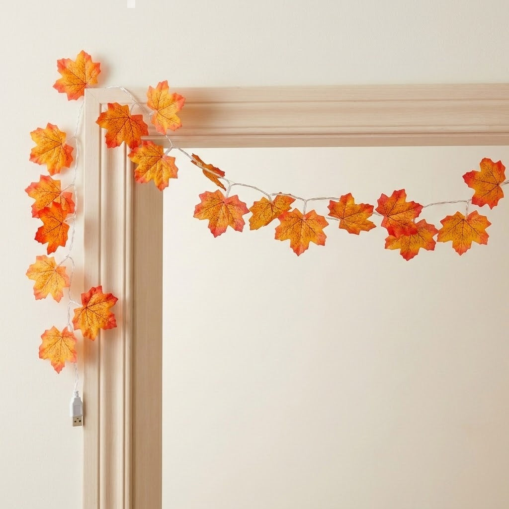 Maple leaf string lights with orange and yellow leaves drape around a beige door frame, with a USB connector hanging below.
