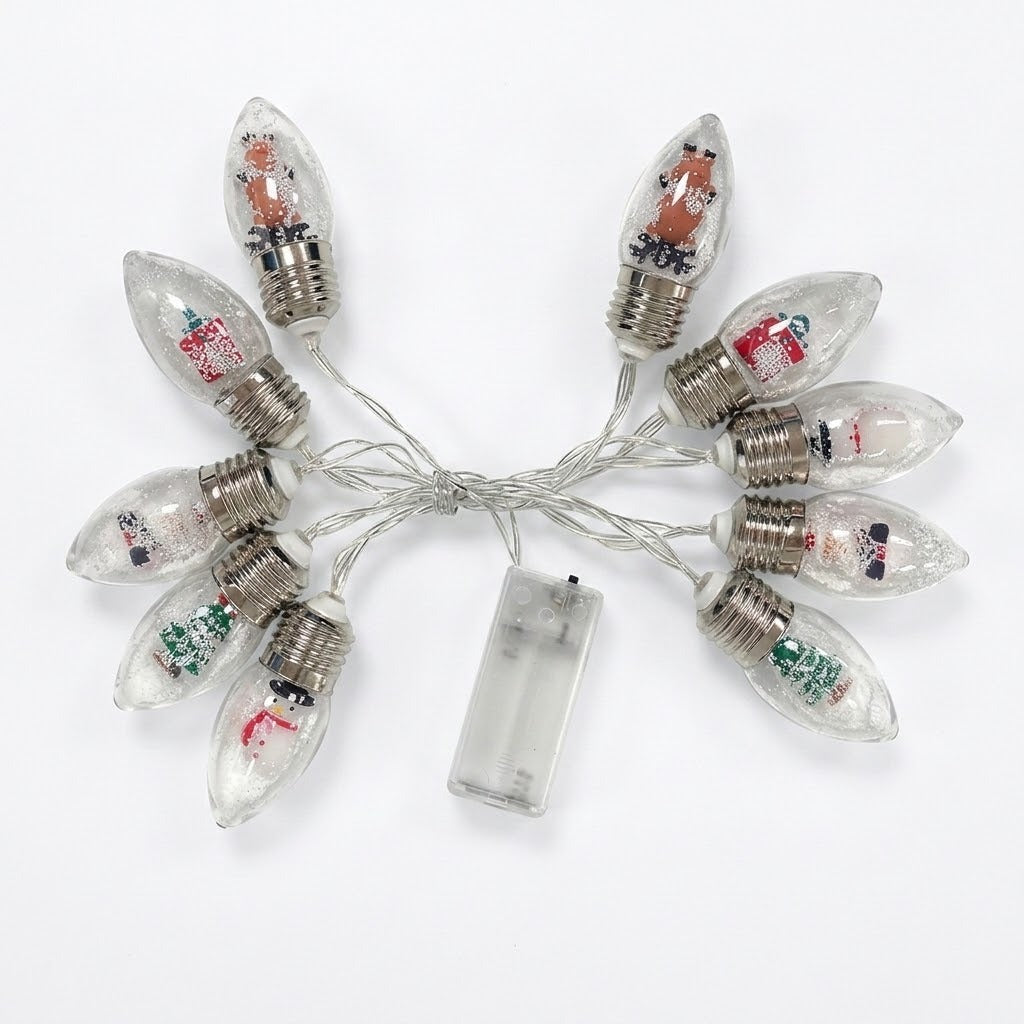 A set of clear C9 Christmas bulb string lights with silver screw bases, filled with decorative glitter and small holiday illustrations, connected by a clear wire to a transparent battery pack on a white background.