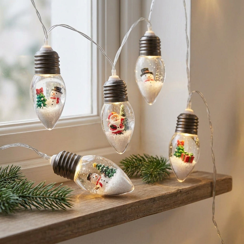 Christmas string lights with clear bulbs containing festive figurines hang beside a window above a wooden shelf with evergreen sprigs.