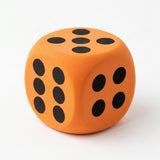 An orange foam die with black dots shows five on top, six on the left, and four on the right against white.