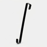 A black zinc alloy wreath hanger stands diagonally against a light background, showing its flat shaft and hooks at both ends.
