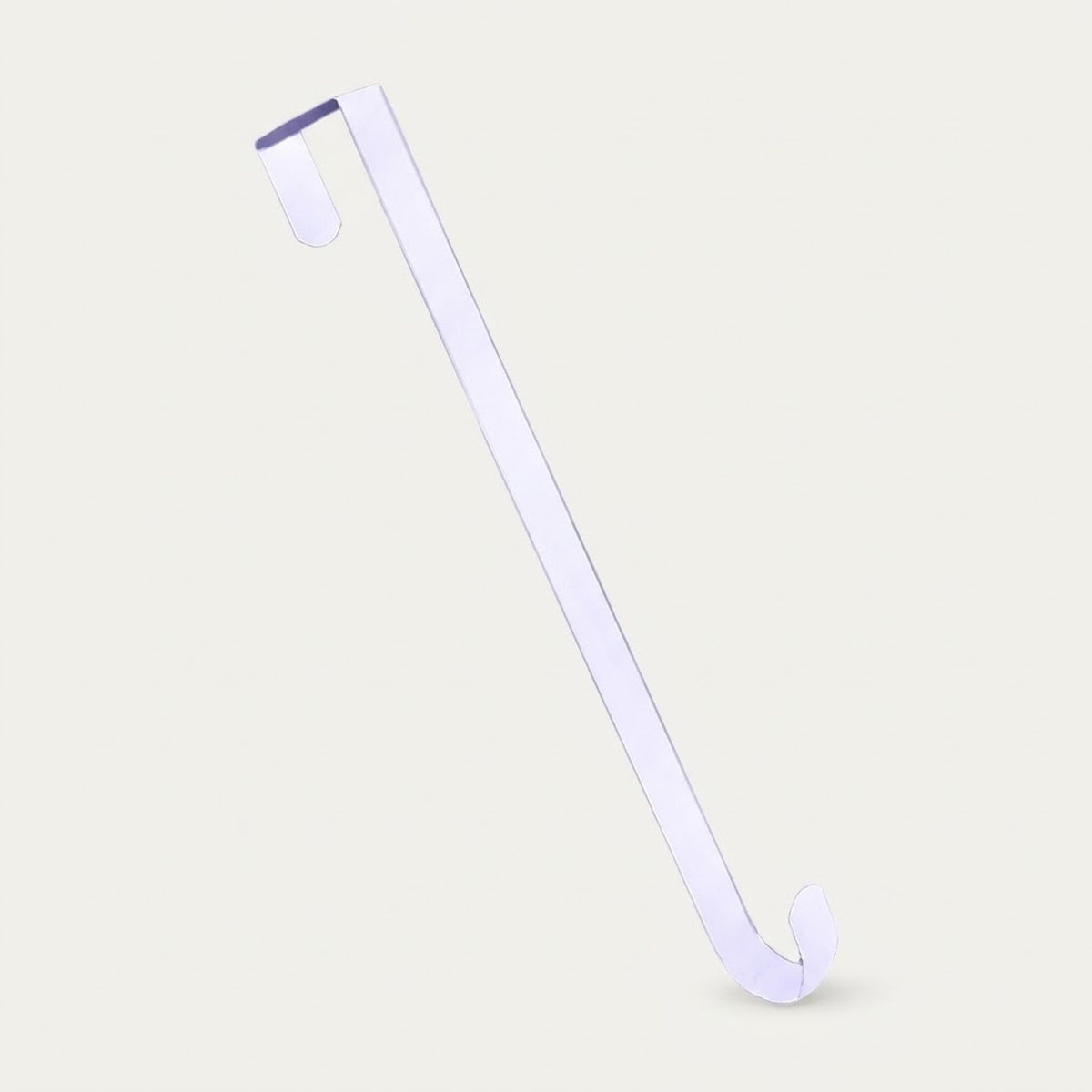 A white zinc alloy wreath hanger stands diagonally against a light beige background, showing its bent top and curved lower hook.