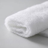 A folded white snow blanket shows fine fuzzy fibers and layered edges in close-up against a light gray background.
