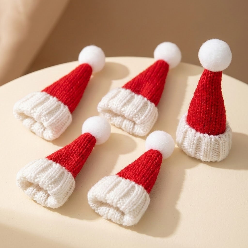 Five miniature Christmas accessories shaped as red knitted Santa hats with white brims and pom-poms sit on a sunlit cream surface.