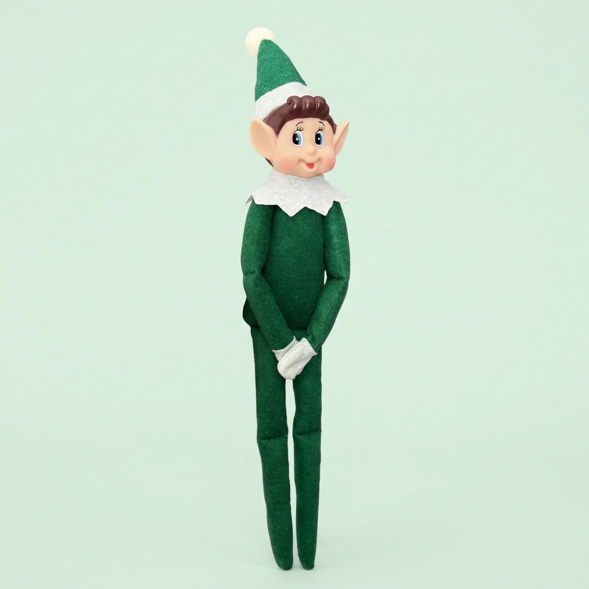 Elf doll with a green fabric outfit, pointed hat, white collar and gloves, and long legs against a pale green background.