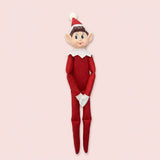 Elf doll with a red fabric outfit, white-trimmed pointed hat, white collar and gloves, and long legs against a pale pink background.