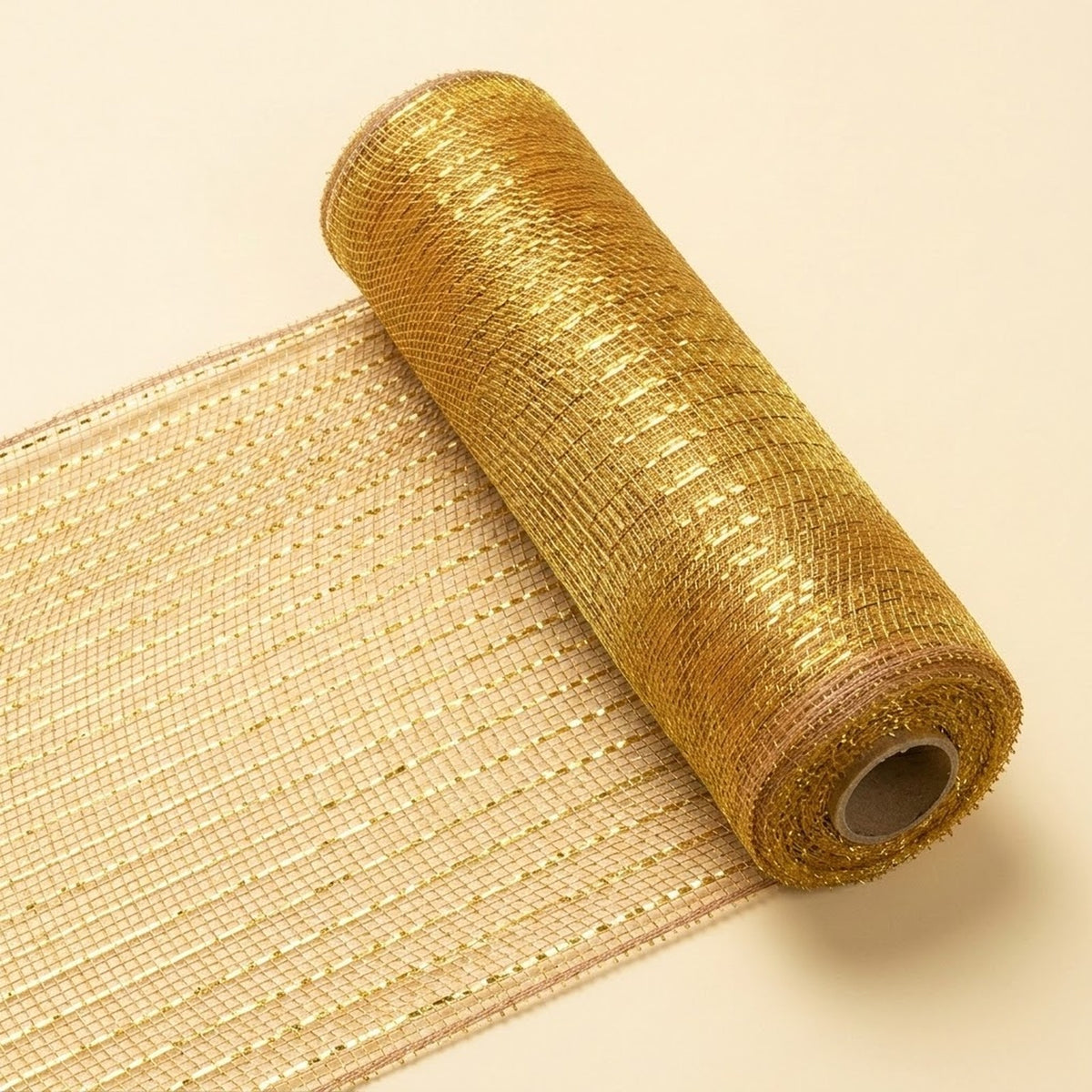 Gold decorative ribbon with an open mesh weave lies partially unrolled diagonally on a cream background, with its cardboard core visible.