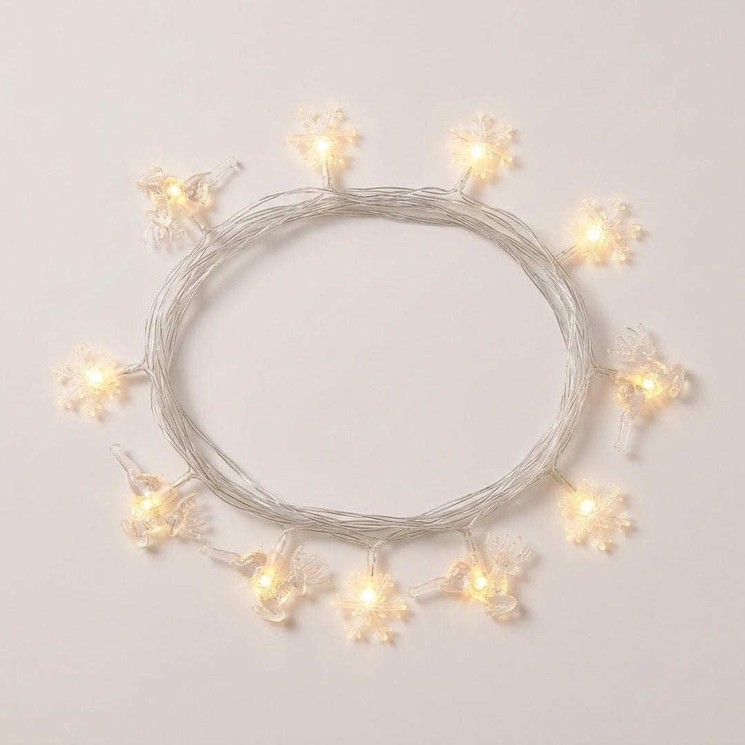 Clear reindeer and snowflake string lights glow warm white around a coil of silver-colored wire on a white background.