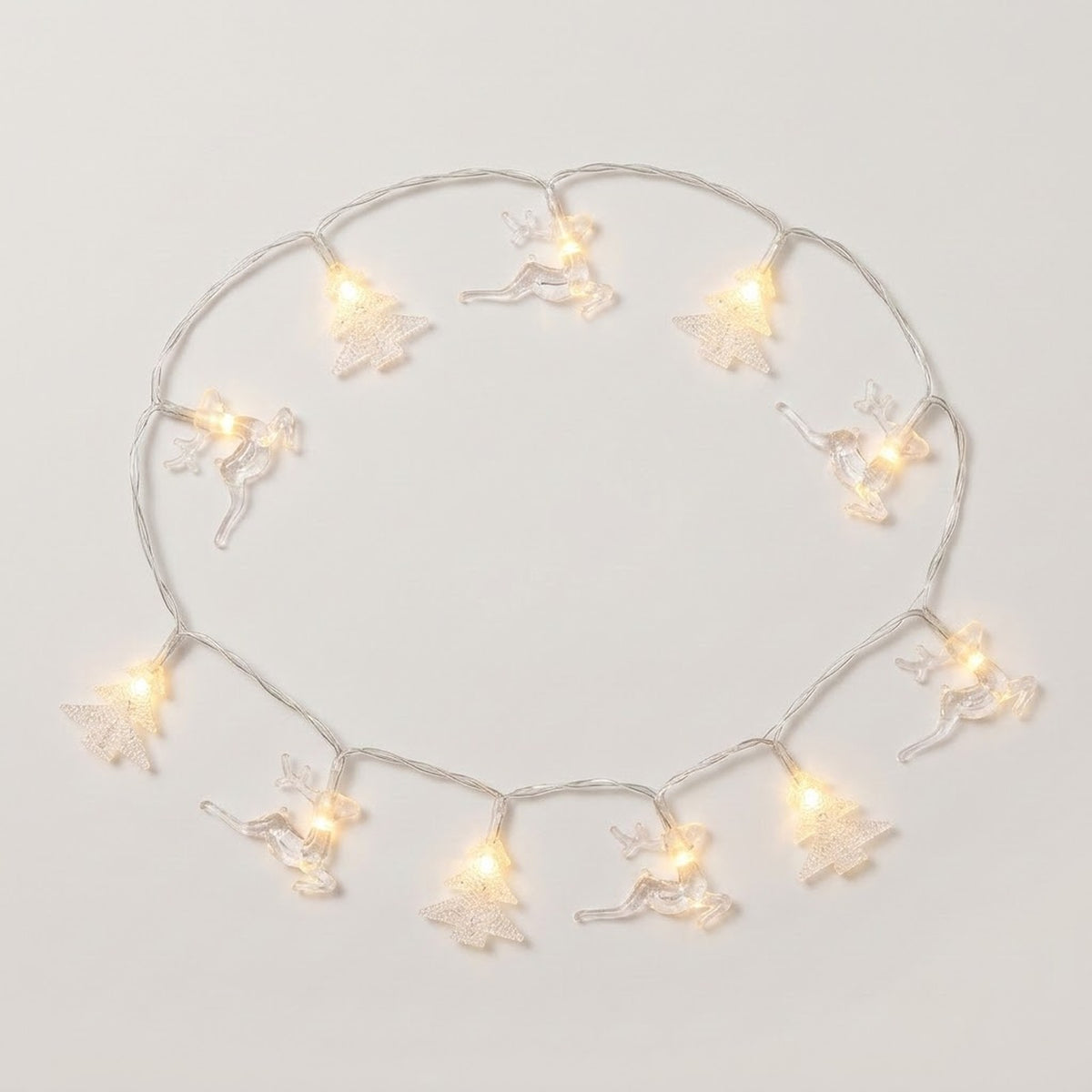Clear reindeer and Christmas tree string lights glow warm white in a loose circle on a white background.