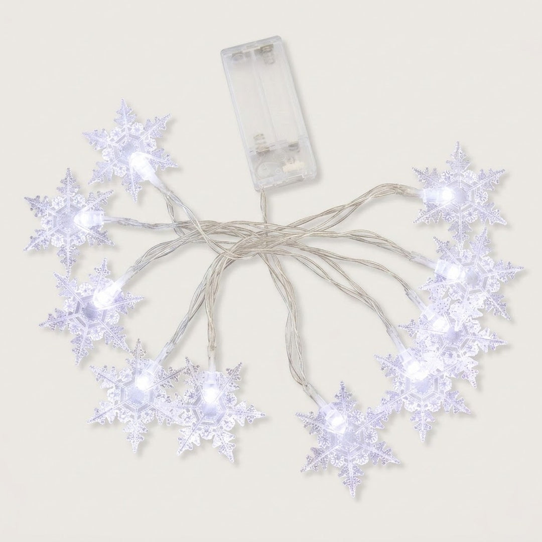 Clear snowflake string lights glow cool white, with silver-colored wires and a transparent battery box on a white background.