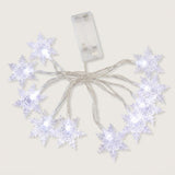 Clear snowflake string lights glow cool white, with silver-colored wires and a transparent battery box on a white background.