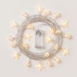 Warm white star and globe string lights surround coiled silver-colored wire and a transparent battery box on a white background.