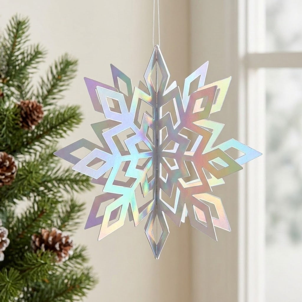 An iridescent silver 3D snowflake ornament hangs beside a window and evergreen branches with pinecones, reflecting pastel rainbow colours.