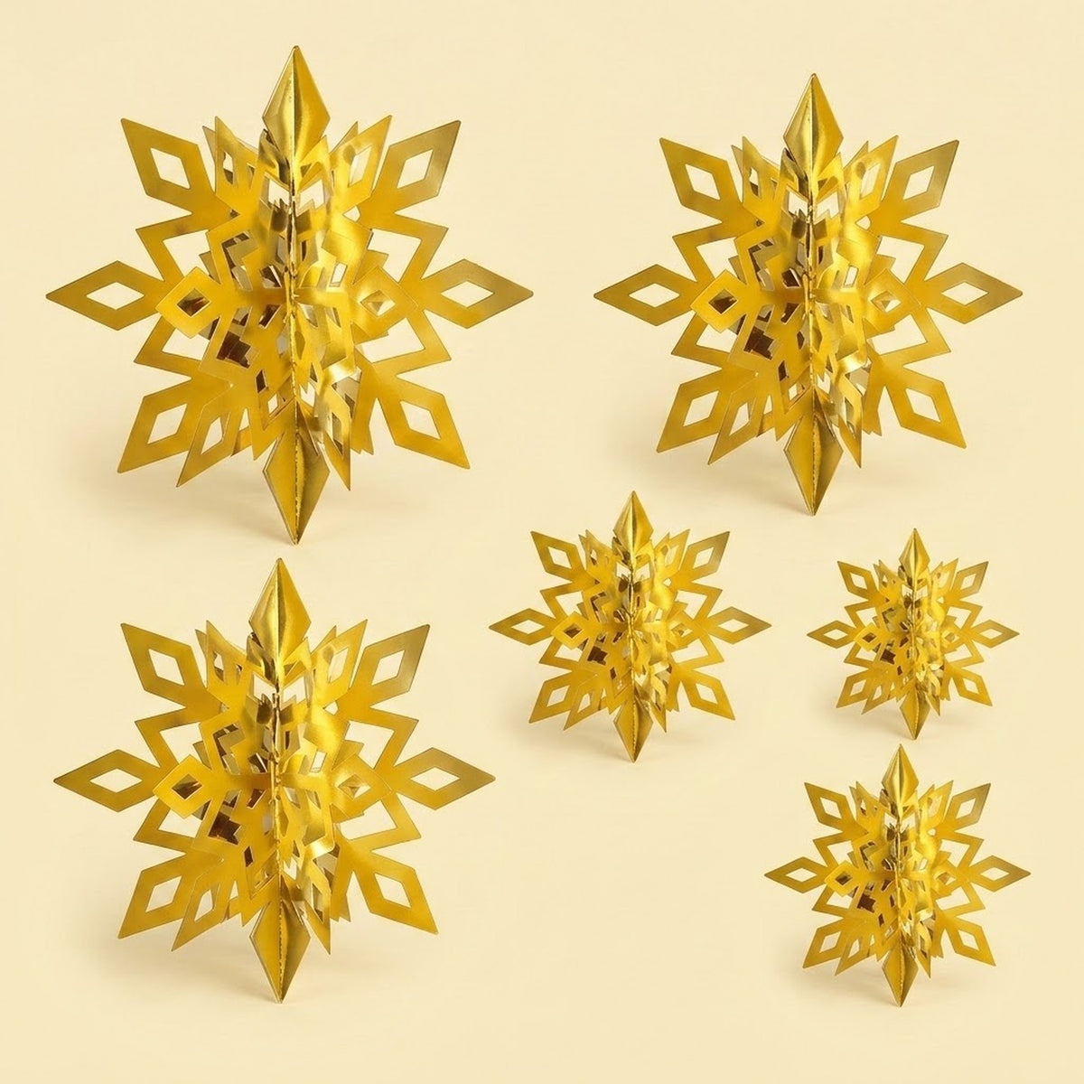 Six reflective gold 3D snowflake ornaments with folded centers and diamond cutouts stand against a pale yellow background.