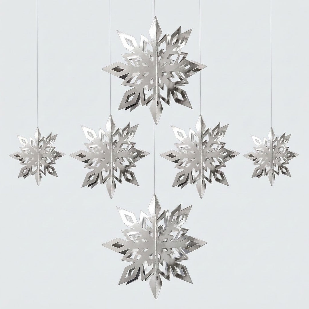 Six reflective silver 3D snowflake ornaments in three sizes hang at staggered heights against a light gray background.