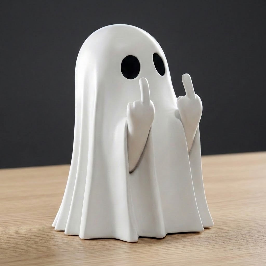 A white ghost figurine with black circular eyes and raised middle fingers, standing on a light wood surface against a dark gray background.
