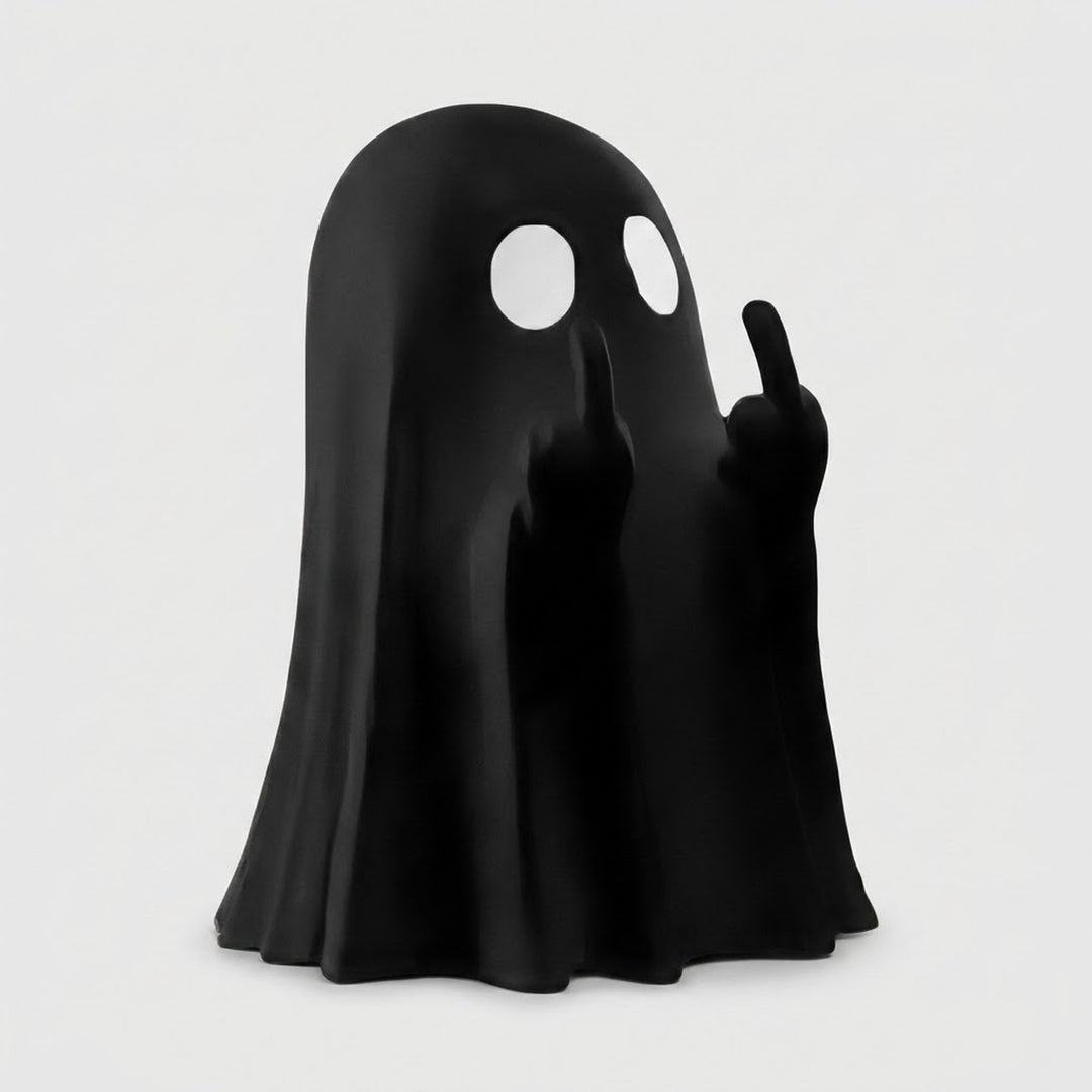 A black ghost-shaped figurine or lamp with two white circular eye cutouts and raised hands showing middle fingers, photographed on a plain light gray background.