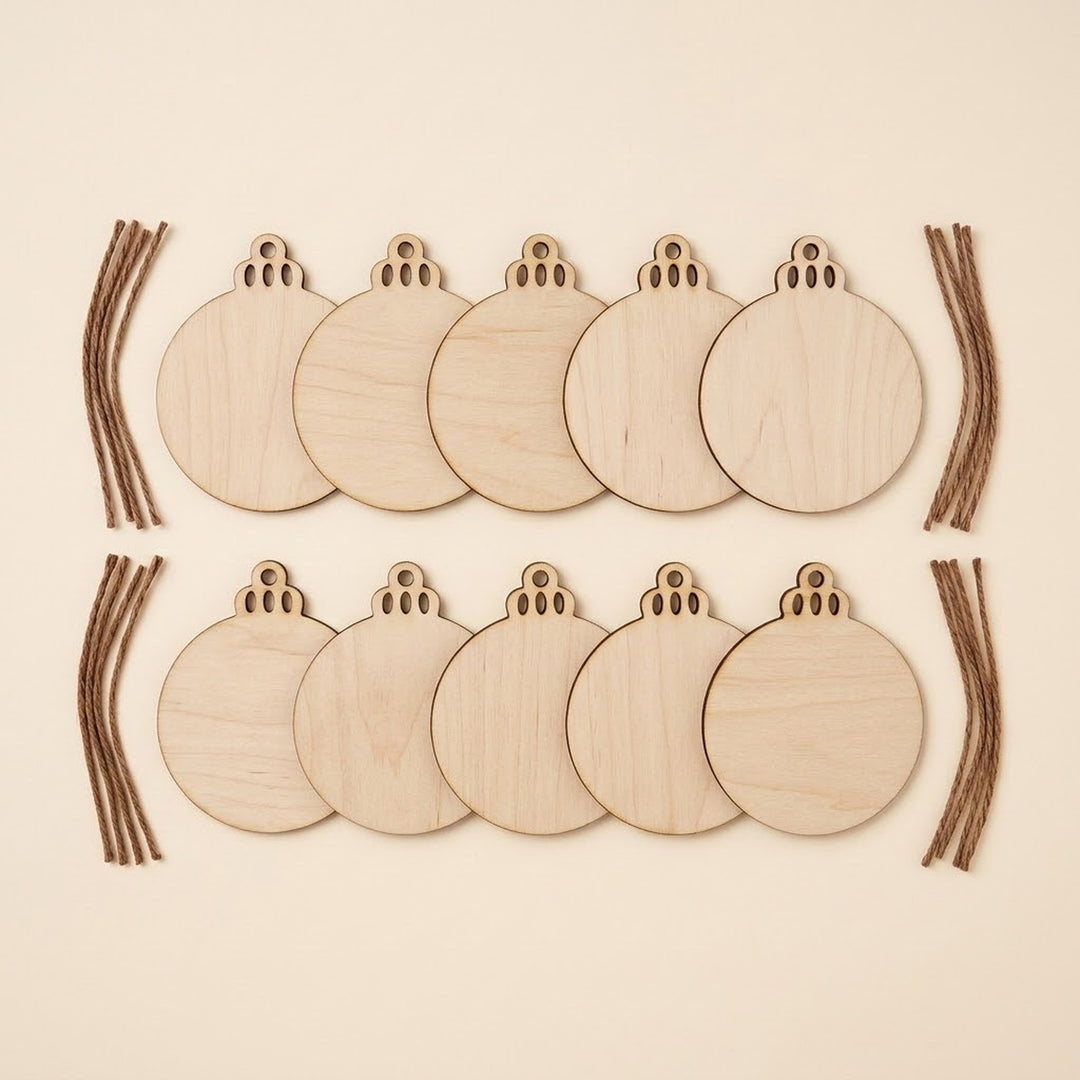 Eight round unfinished wooden ornament blanks arranged in two rows on a light beige background, with several brown string pieces placed along the left and right sides.