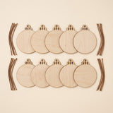 Eight round unfinished wooden ornament blanks arranged in two rows on a light beige background, with several brown string pieces placed along the left and right sides.