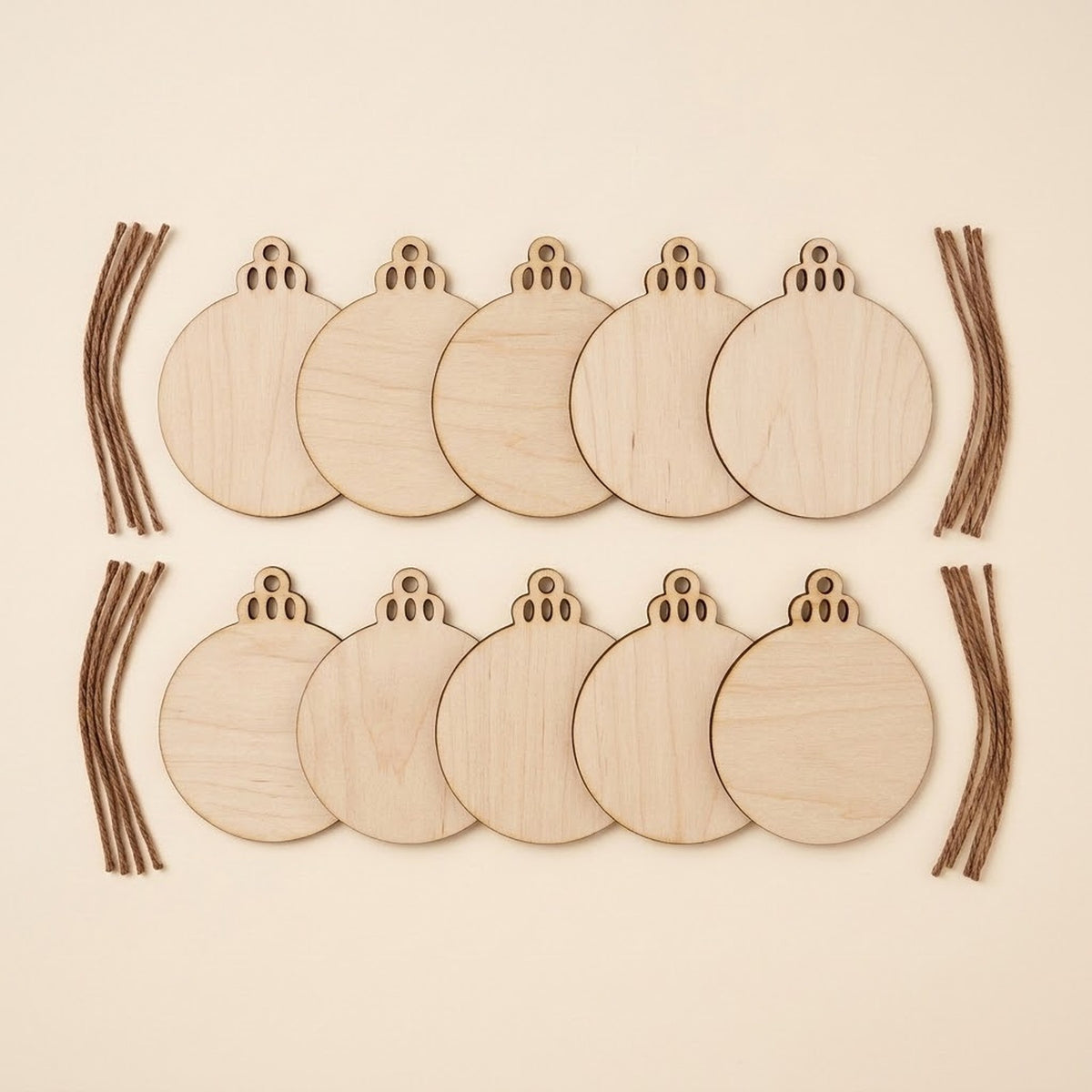 Eight round unfinished wooden ornament blanks arranged in two rows on a light beige background, with several brown string pieces placed along the left and right sides.
