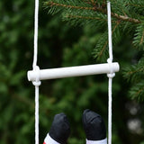 A close-up of the hanging Christmas decoration shows white ladder ropes, a white rung and Santa’s black boots against evergreen branches.