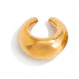 A gold-tone ear cuff rests on a white background with its broad curved face and open ends visible.