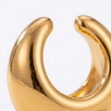 A close-up shows the gold-tone ear cuff’s reflective surface, rounded tips, and inner curve against a white background.