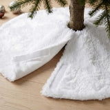 A close-up shows the white fluffy tree skirt opened around a brown trunk, revealing white fastening strips above a wooden floor.