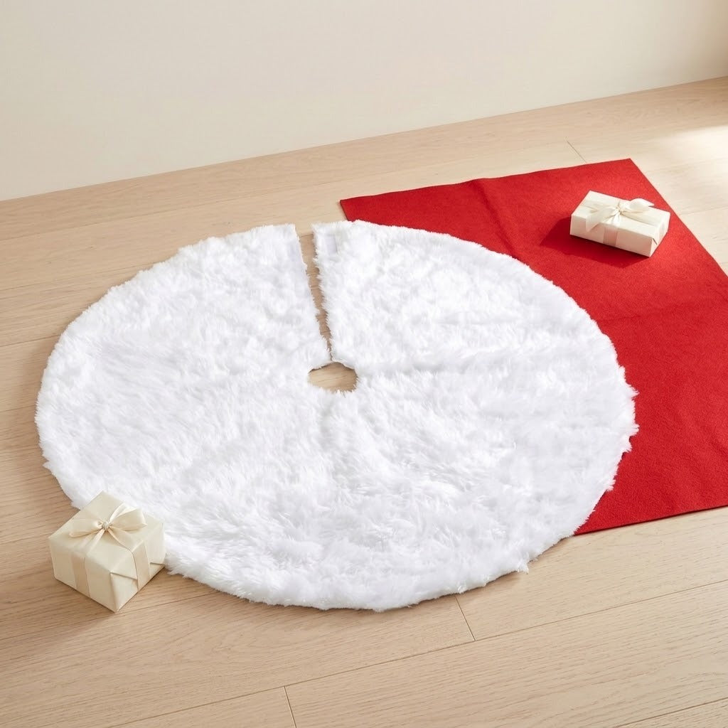 A white fluffy tree skirt with a central opening and radial slit lies beside red fabric and cream gifts on a wooden floor.