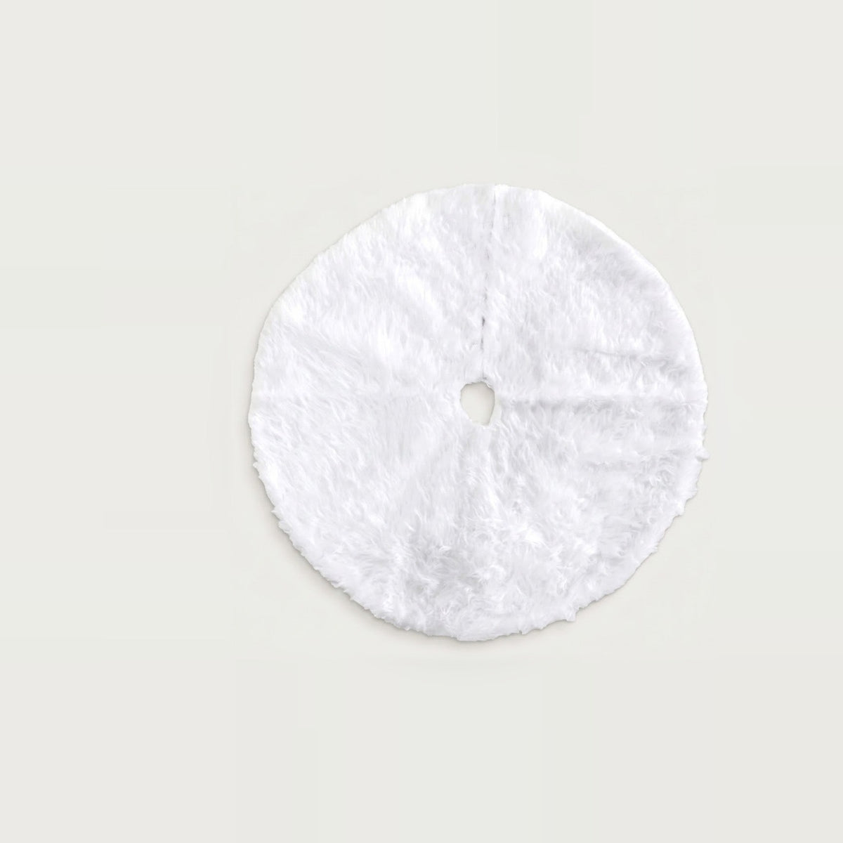 White plush Christmas tree skirt laid flat on a pale background, showing a round shape, center hole, and opening slit.