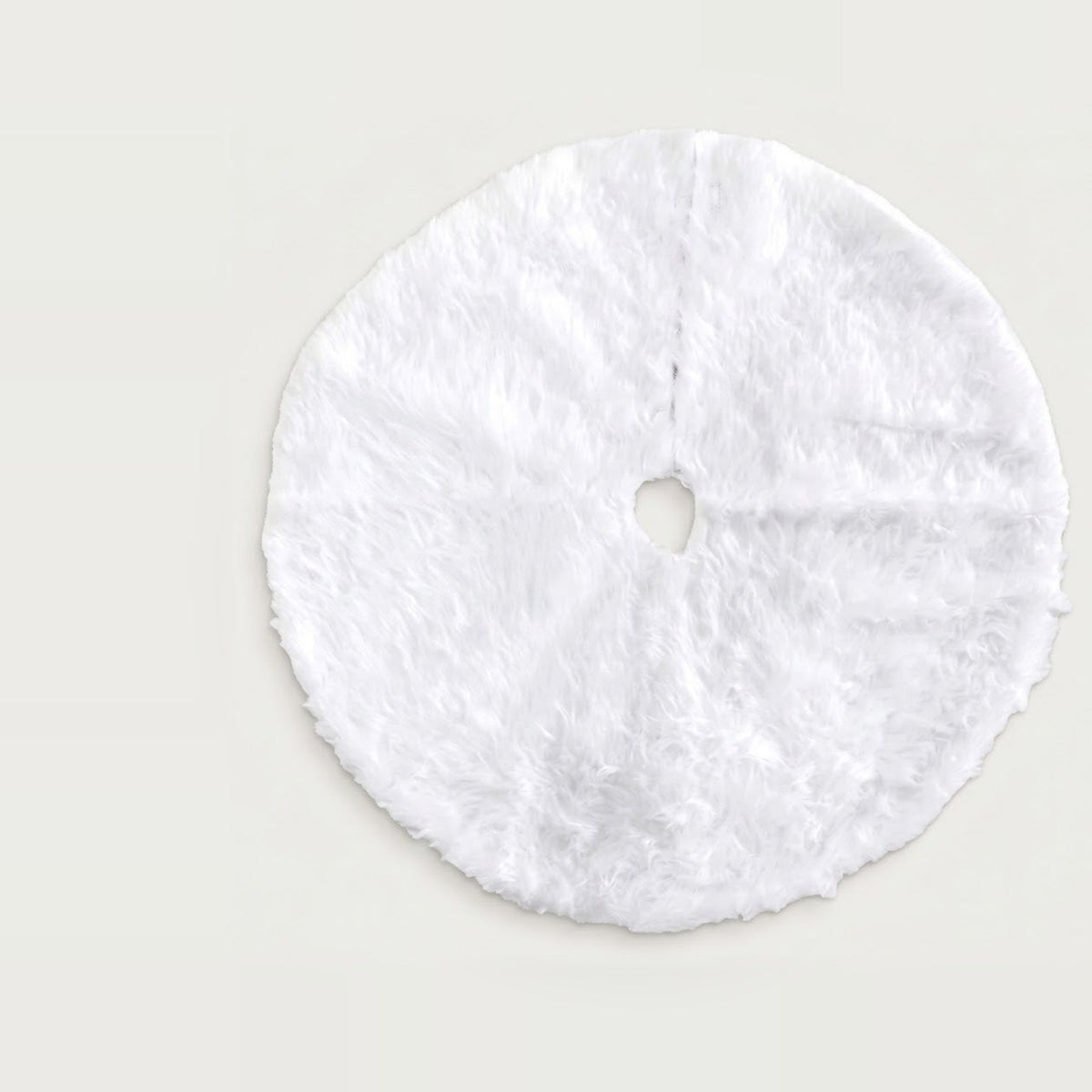 White fluffy circular Christmas tree skirt with a central opening and radial slit, laid flat on a light background.