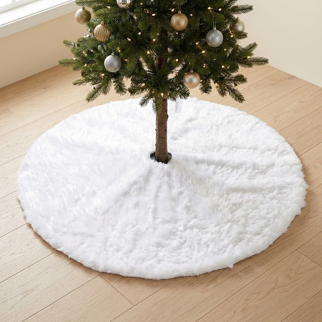 A round white fluffy tree skirt lies beneath a Christmas tree decorated with gold and silver ornaments on a pale wooden floor.