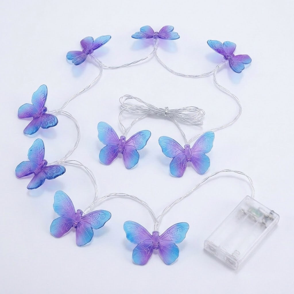 Unlit purple and blue butterfly string lights with silver wire and a clear battery box rest on a white background.