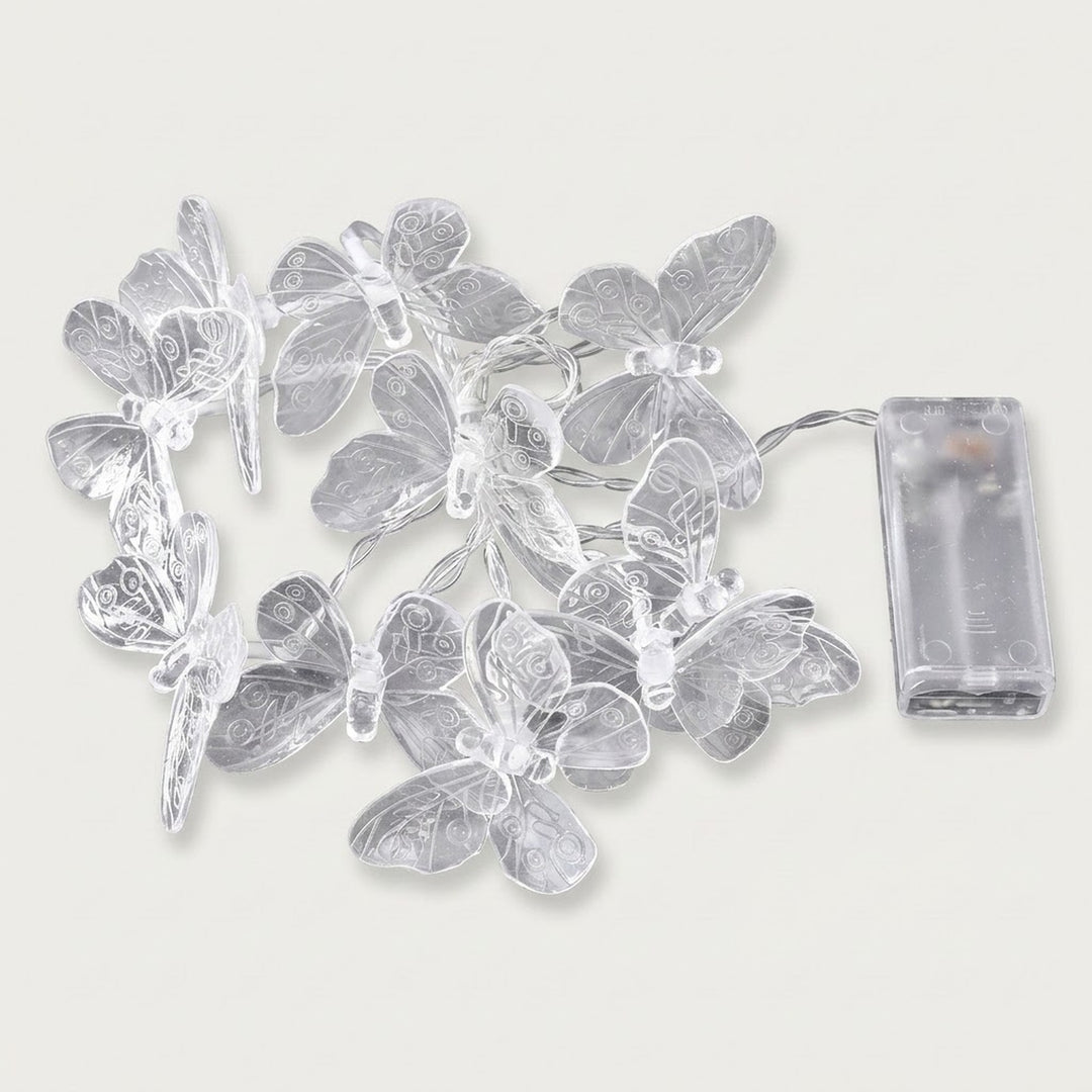 Unlit clear butterfly string lights with patterned wings and silver wire lie beside a transparent battery box on a white background.