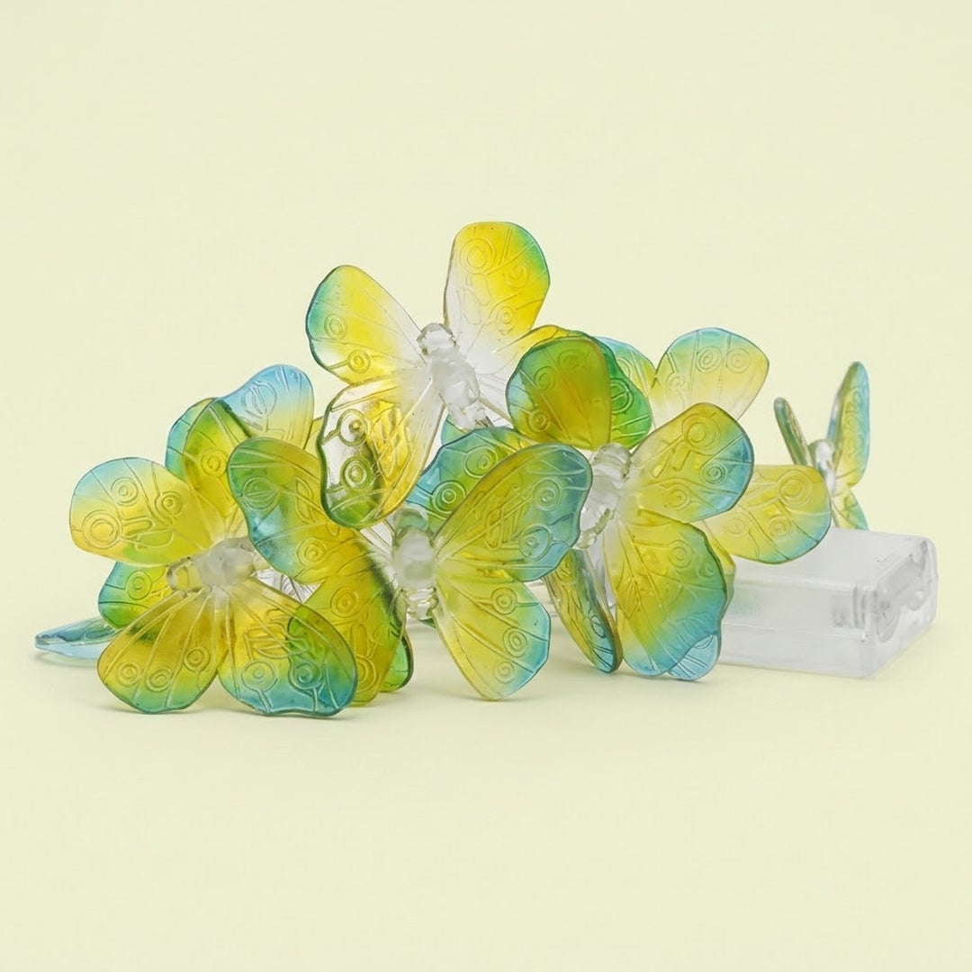 Translucent green and yellow butterfly string lights sit clustered beside a clear battery box against a pale yellow background.