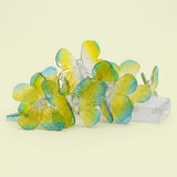 Translucent green and yellow butterfly string lights sit clustered beside a clear battery box against a pale yellow background.