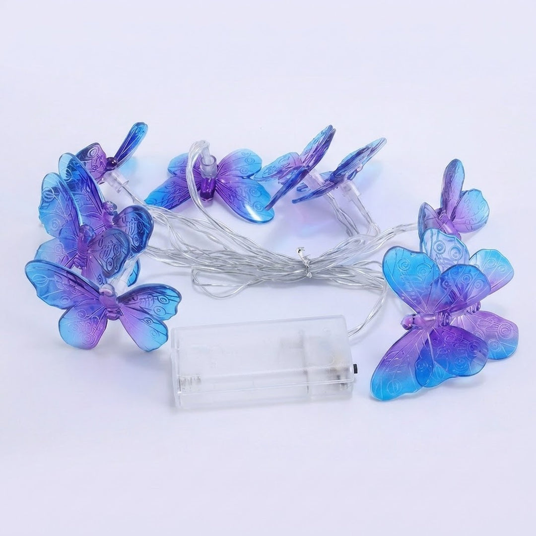 Unlit purple and blue butterfly string lights surround bundled silver wire and a clear battery box on a pale background.