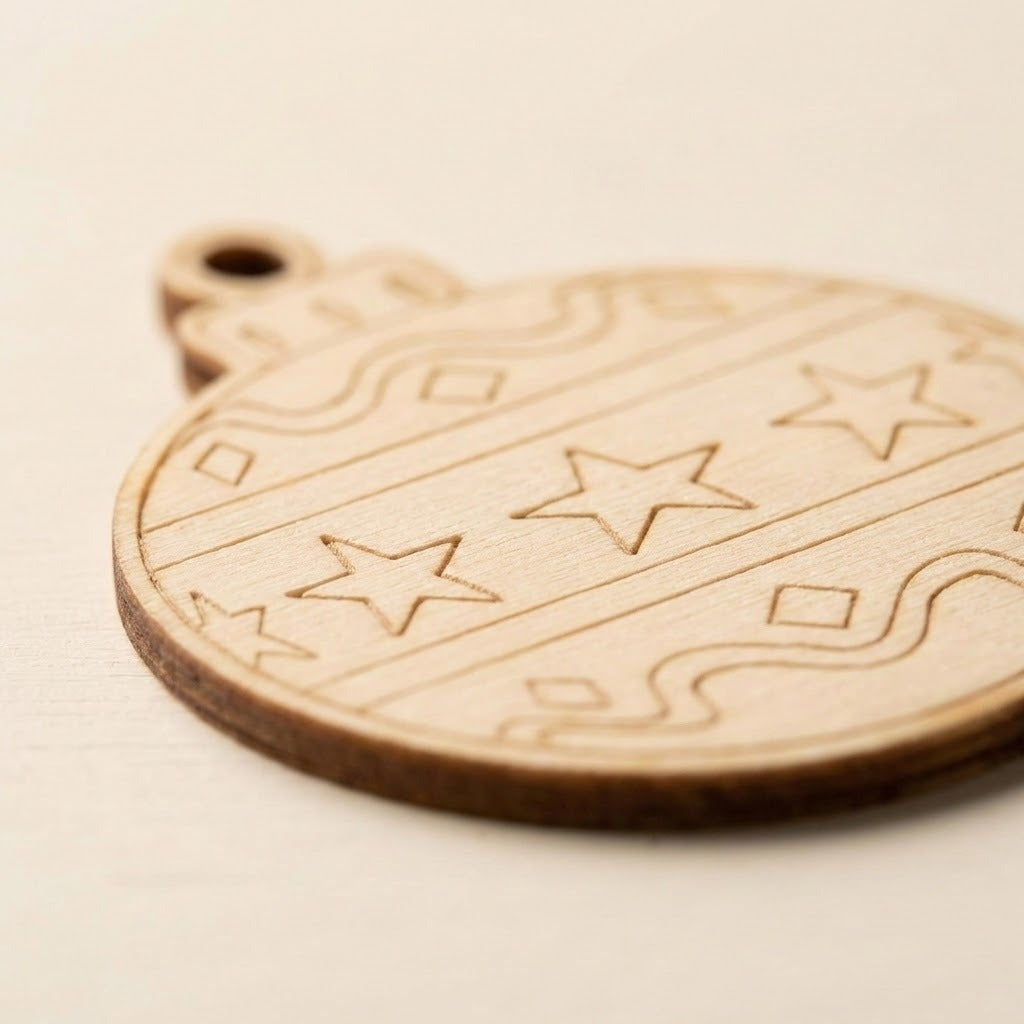 Close-up of an unfinished wood ornament craft set piece shows etched stars, wavy lines, and a dark edge against a cream background.