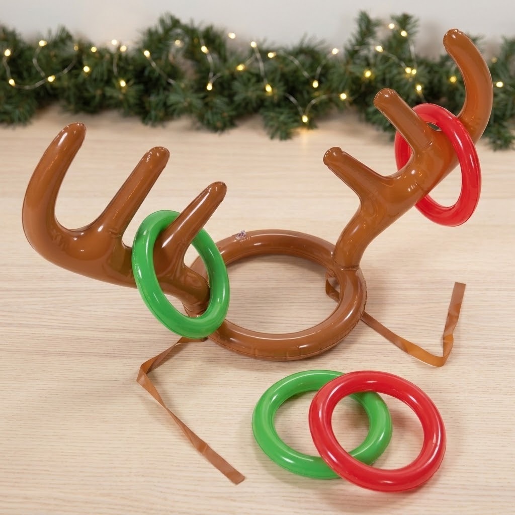 A reindeer-themed plastic ring toss game on a light wood tabletop, with green and red plastic rings around a brown reindeer head and antlers. A garland with warm string lights is blurred in the background.