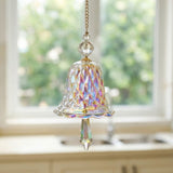 An iridescent bell-shaped glass suncatcher with faceted beads and a pointed drop hangs from a gold-tone chain above a kitchen sink.