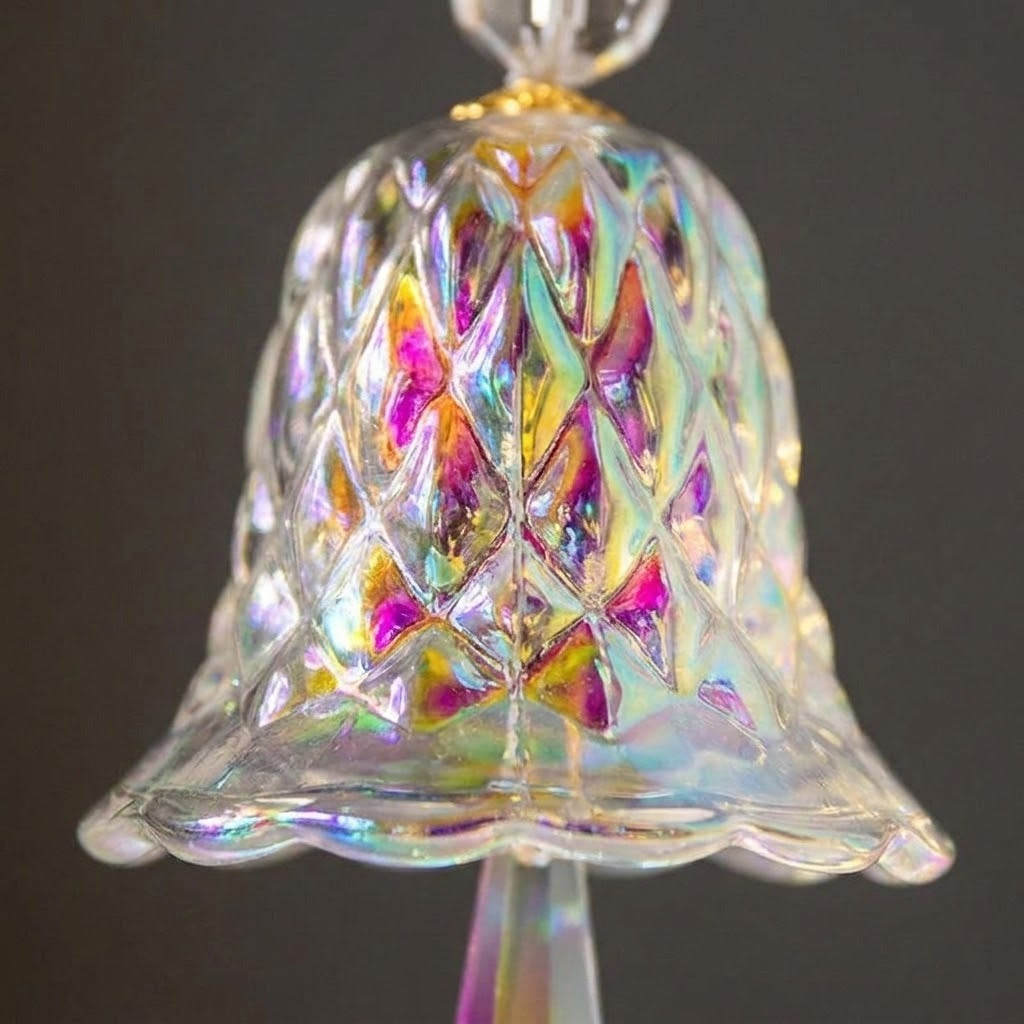 A close-up of an iridescent glass suncatcher shows its diamond-patterned bell, scalloped rim, and rainbow reflections against a dark background.