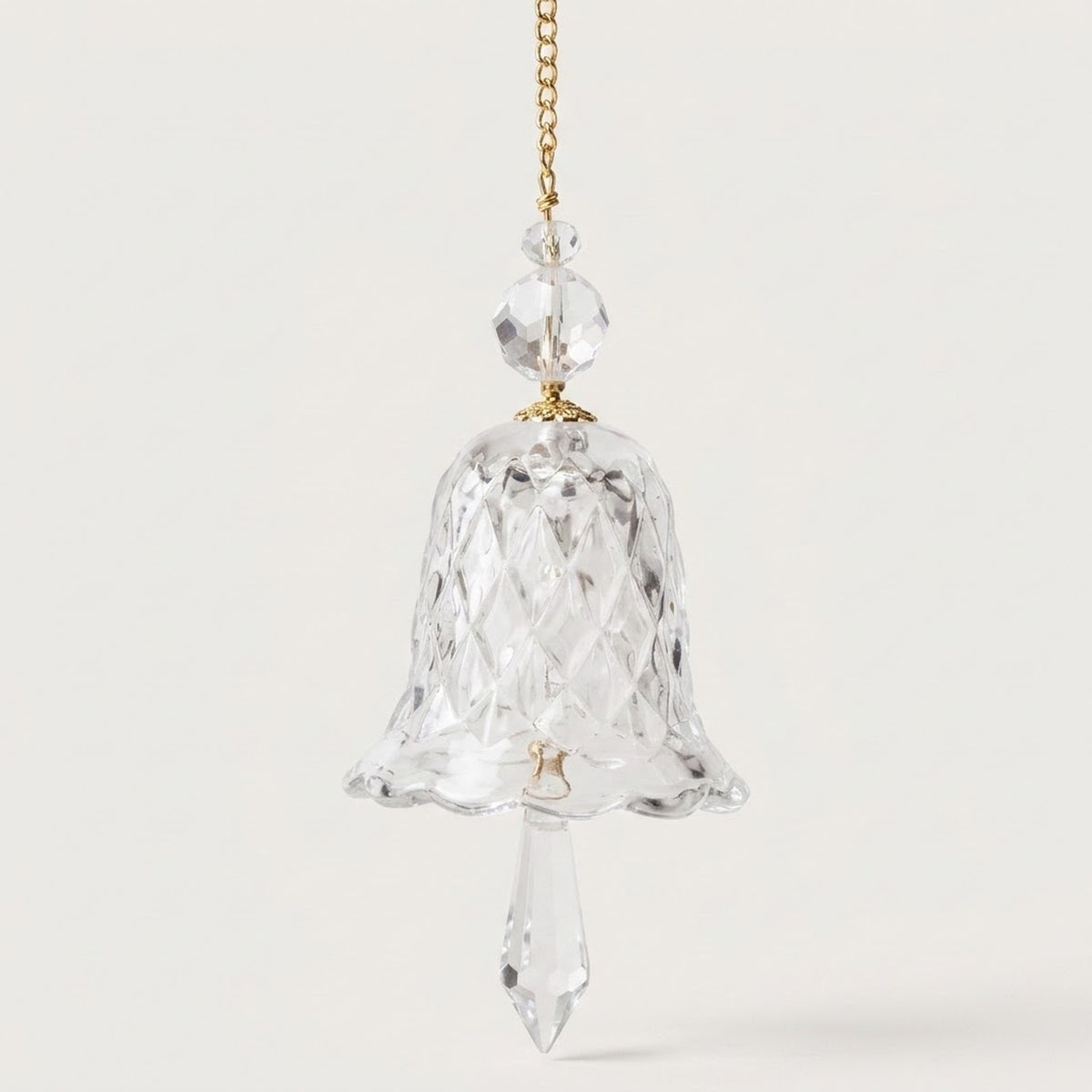 A clear bell-shaped glass suncatcher with a scalloped rim, two faceted beads, and a pointed drop hangs against a white background.
