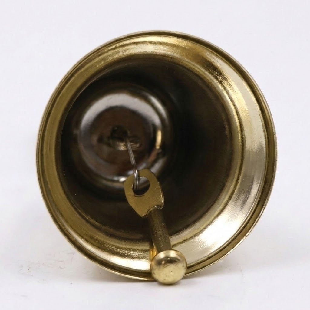 A gold hand bell viewed from underneath shows its metal clapper and flared circular rim against a white background.